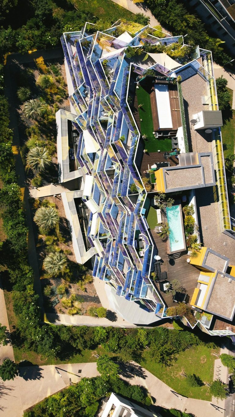 Aerial view of a modern residential building with unique architecture and rooftop pool.