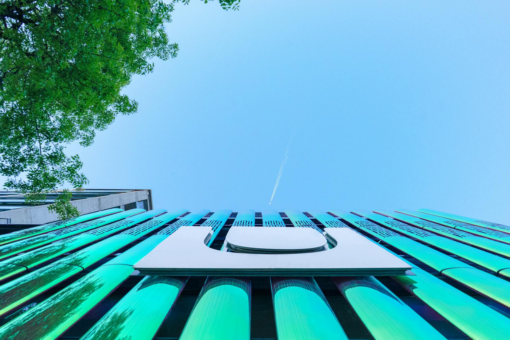 Low-angle view of a modern building facade with reflective surfaces and clear blue sky.