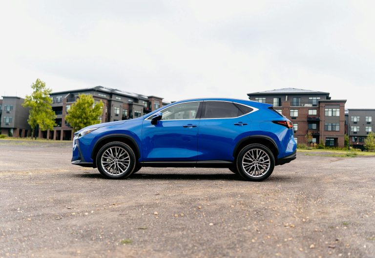 Side profile of a blue SUV in an outdoor urban environment with modern buildings.