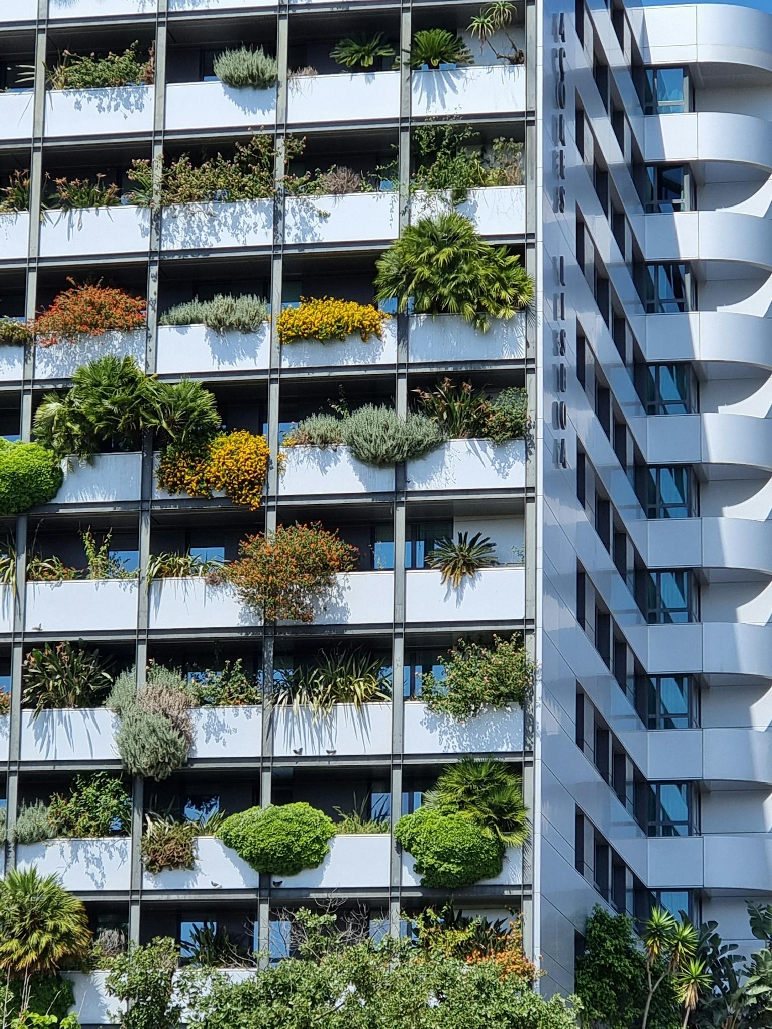 Vertical urban building facade covered with lush greenery and plants, showcasing modern architecture.